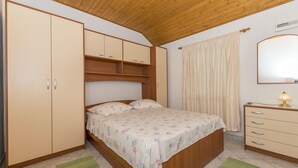 A bedroom with a wooden bed, a wardrobe, a dresser, and a mirror. - House Santa Barbara (Postira)