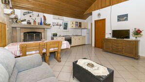 A cozy living room with a fireplace, a dining area, a kitchen, and a TV. - House Santa Barbara (Postira)