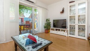 A living room with a glass table, a TV, a cabinet with glass doors, and a potted plant. - Apartments Anita (Vrboska)