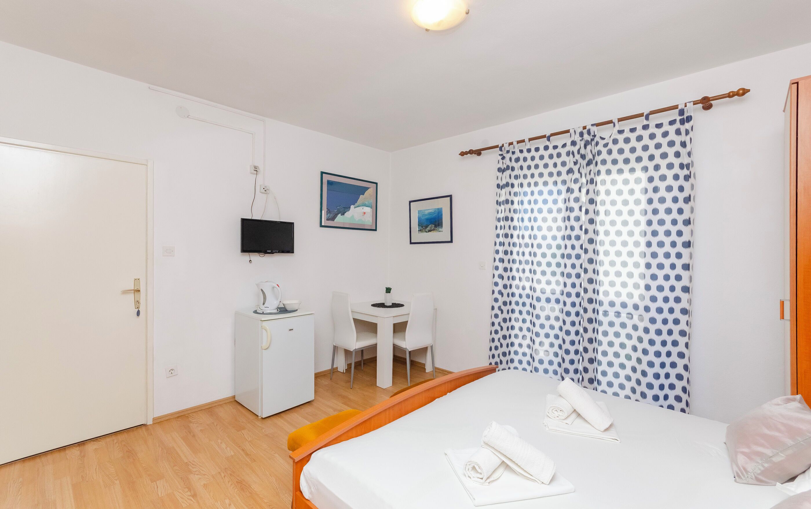 A hotel room with a bed, a desk, a chair, a television, and a shower curtain.