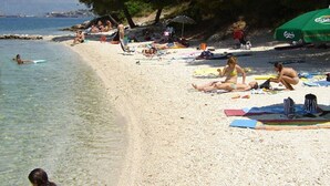 A beach with people sunbathing and swimming. - Apartments Marko (Okrug Donji)