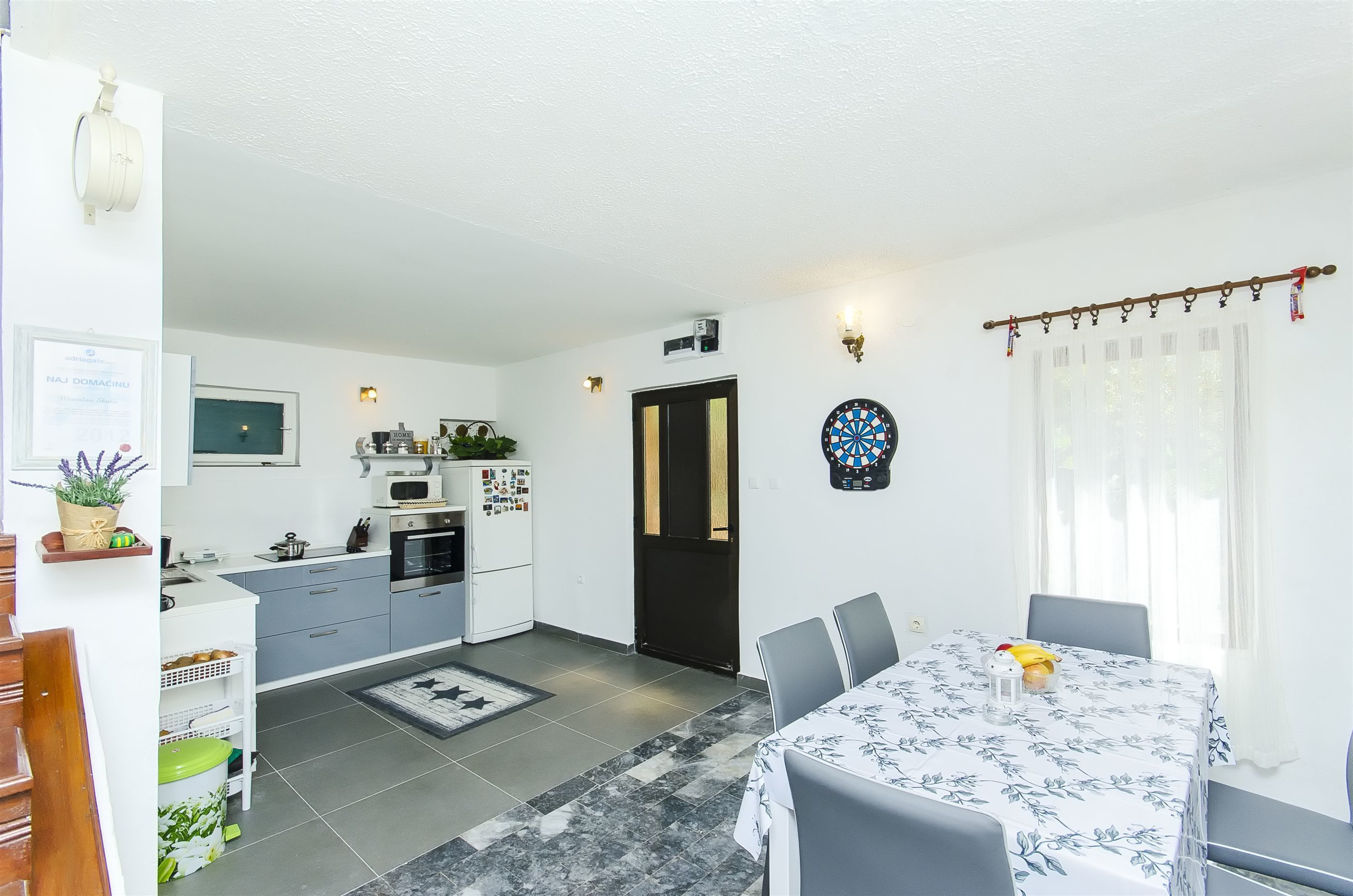 A compact kitchen with a microwave, oven, and refrigerator. There is a dining area with a table and chairs, and a door leading to another room.