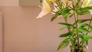 Eine Küche mit einer Vase voller weißer Lilien und einer Schüssel mit Granatapfeln auf dem Tisch.