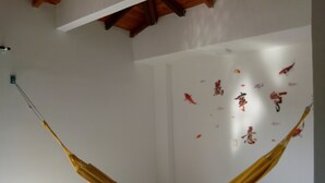 Ett rum med en hängmatta som hänger från taket, en grön stol och en vägg dekorerad med klistermärken föreställande fiskar.