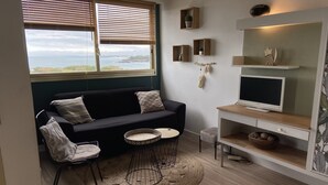 A cozy living area with a dark-colored sofa, a round coffee table, and a TV on a wooden stand. - MAGNIFICENT OCEAN VIEW BIARRITZ (Biarritz)
