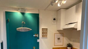 A teal door with a hanging light fixture, a kitchen with white cabinets and a wooden countertop, and a small potted plant on the counter. - MAGNIFICENT OCEAN VIEW BIARRITZ (Biarritz)