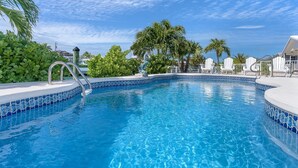 A clear blue pool with a tiled edge, surrounded by white lounge chairs and palm trees. - AUGUST Opening, Fishermen, Couples, Families, Pool, Cabana Club (Key Colony Beach)