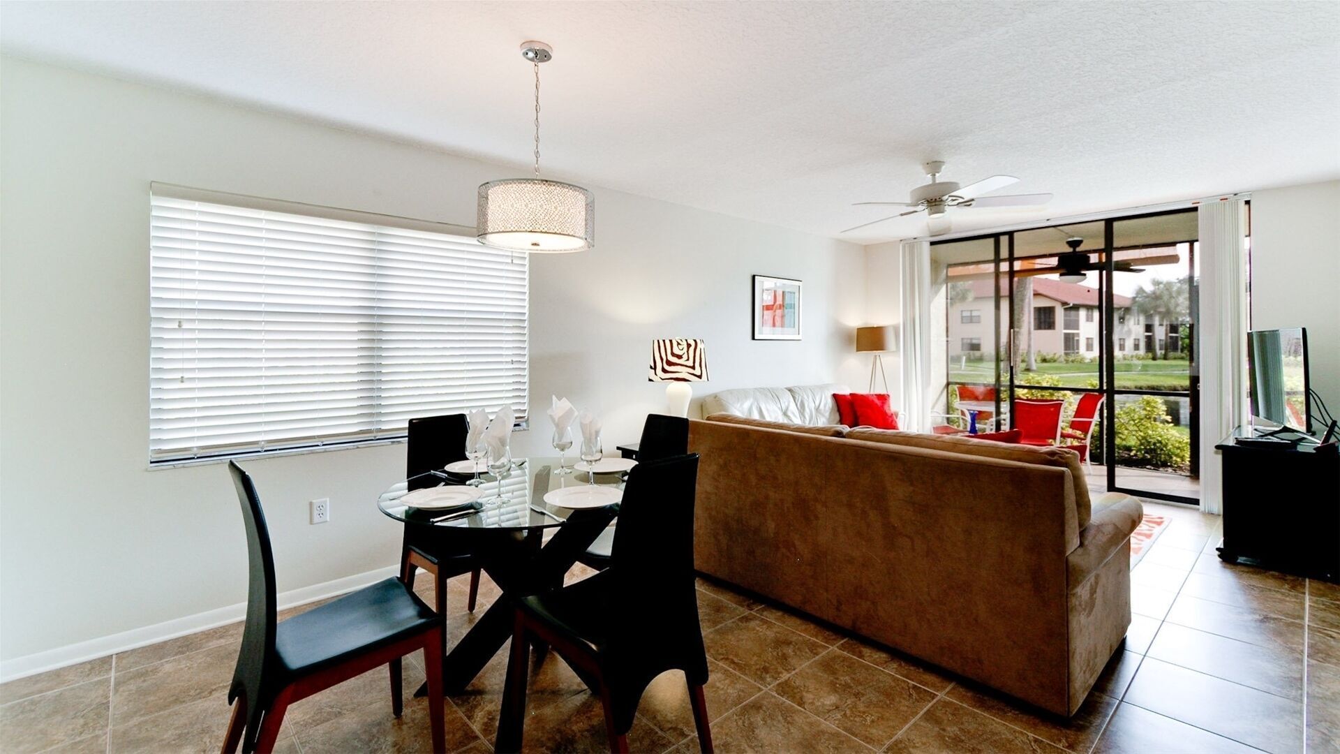 A modern living room with a dining area, a sofa, and a ceiling fan.