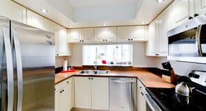 Una cocina moderna con armarios blancos, electrodomésticos de acero inoxidable y una ventana con vistas.