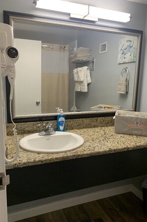 A bathroom with a large mirror, a white sink, a hairdryer, and a towel rack. - Lee's Myrtle Beach Condo (Myrtle Beach)