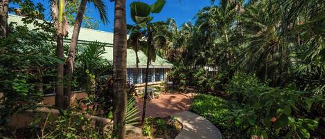 Un jardín exuberante con un sendero curvo que conduce a un edificio con techo verde.