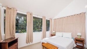 Une chambre à coucher comprenant un lit, des tables de chevet en bois, un banc en bois et une commode.