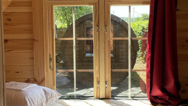 Una habitación de cabaña de madera con una cama, un ventanal y una puerta.