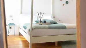 Un dormitorio con una cama con dosel, una mesita de noche, una lámpara y una alfombra pequeña.