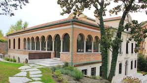 Un edificio con fachada de ladrillo, ventanas de arco y techo verde.
