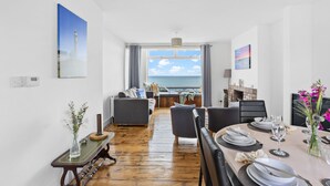 A dining area with a view of the sea, a fireplace, and a table set for dining. - Lighthouse View - Woodburner & Sea View (Brixham)