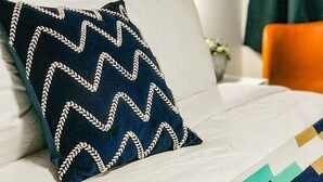 A neatly made bed with a patterned pillow, a white headboard, and a green curtain. - Stonewall Motor Lodge (Stonewall)