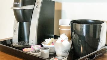 A coffee maker, a mug, and a tray with coffee pods and a cup.