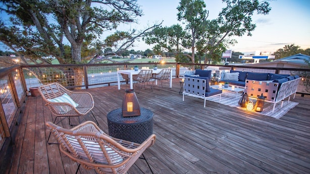 A wooden deck with wicker chairs and a sofa, a table with candles, and a lantern. - Stonewall Motor Lodge (Stonewall)