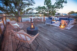A wooden deck with wicker chairs and a sofa, a table with candles, and a lantern.