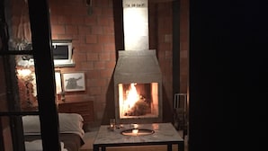 Ein Kamin aus Ziegelsteinen mit Feuer, ein kleiner Tisch davor und ein Schild darüber.