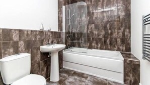 A bathroom with a toilet, pedestal sink, and a bathtub. - City Suites by Guestz (Chester)
