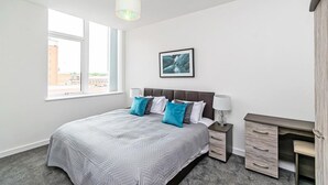 A bedroom with a bed, bedside tables, a desk, and a window. - City Suites by Guestz (Chester)