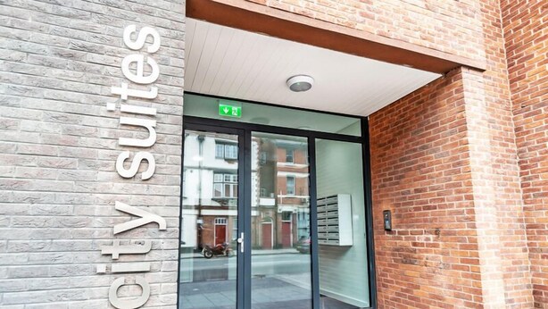 A hotel entrance with a sign reading "City Suites" and an emergency exit sign above the door. - City Suites by Guestz (Chester)