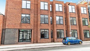 A multi-story brick building with a modern design, featuring large windows and a visible entrance.