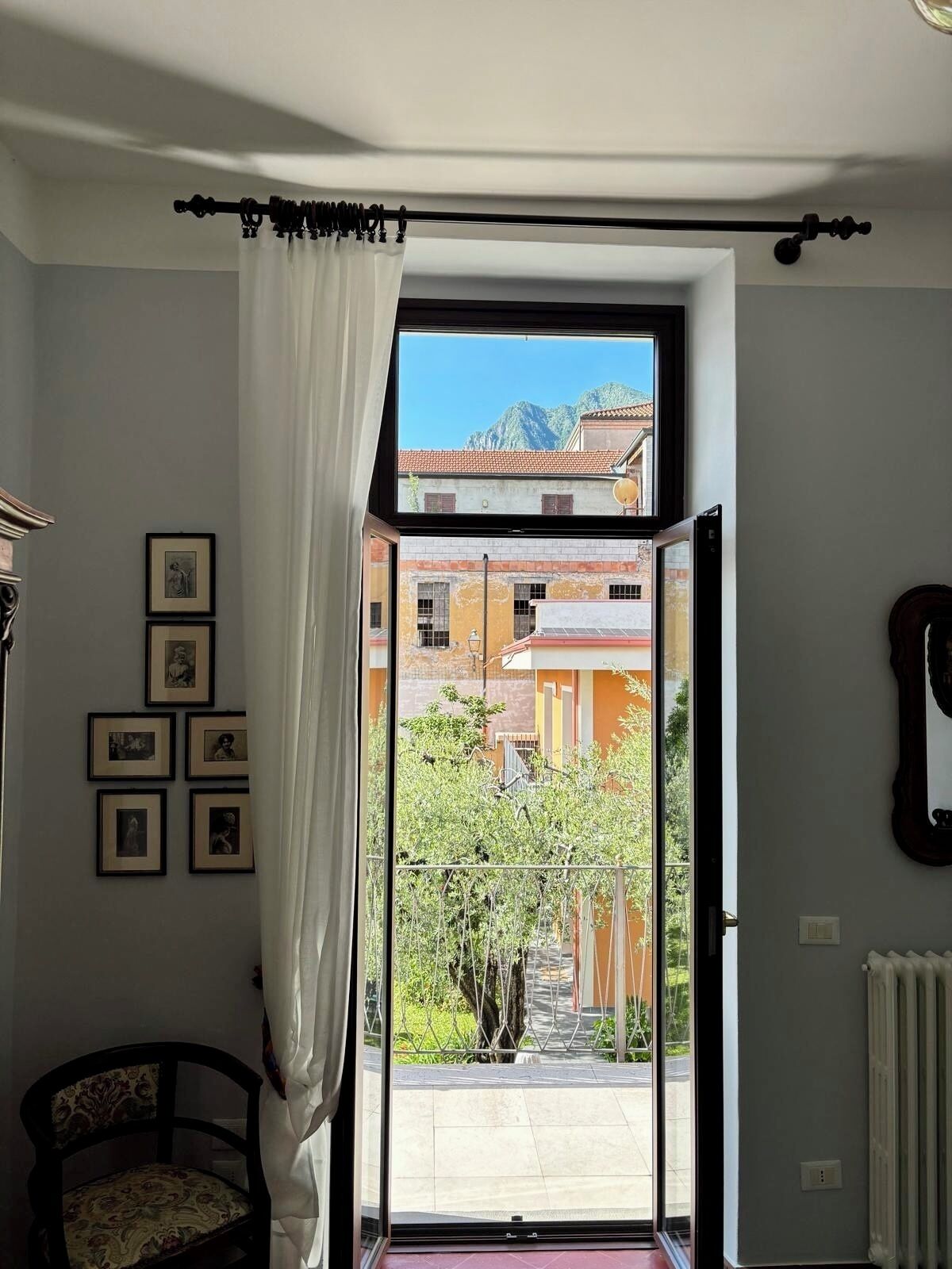 A room with a large window, a chair, and framed pictures on the wall.