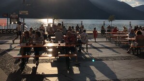 Une terrasse au bord du lac, avec des tables et des chaises, d’où l’on peut admirer un plan d’eau et des montagnes.
