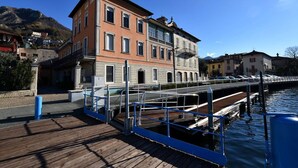 Un bâtiment situé au bord de l’eau, avec une jetée en bois, un pont et une montagne en arrière-plan.