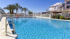 A clear blue swimming pool with a white fence and palm trees in the background. - F04 Bahia Playa - Apartment (Mijas Costa)