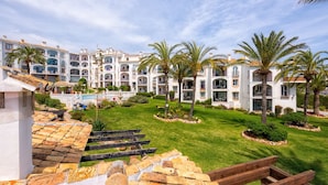 A resort with multiple-story buildings, a well-maintained lawn, and palm trees. - F04 Bahia Playa - Apartment (Mijas Costa)