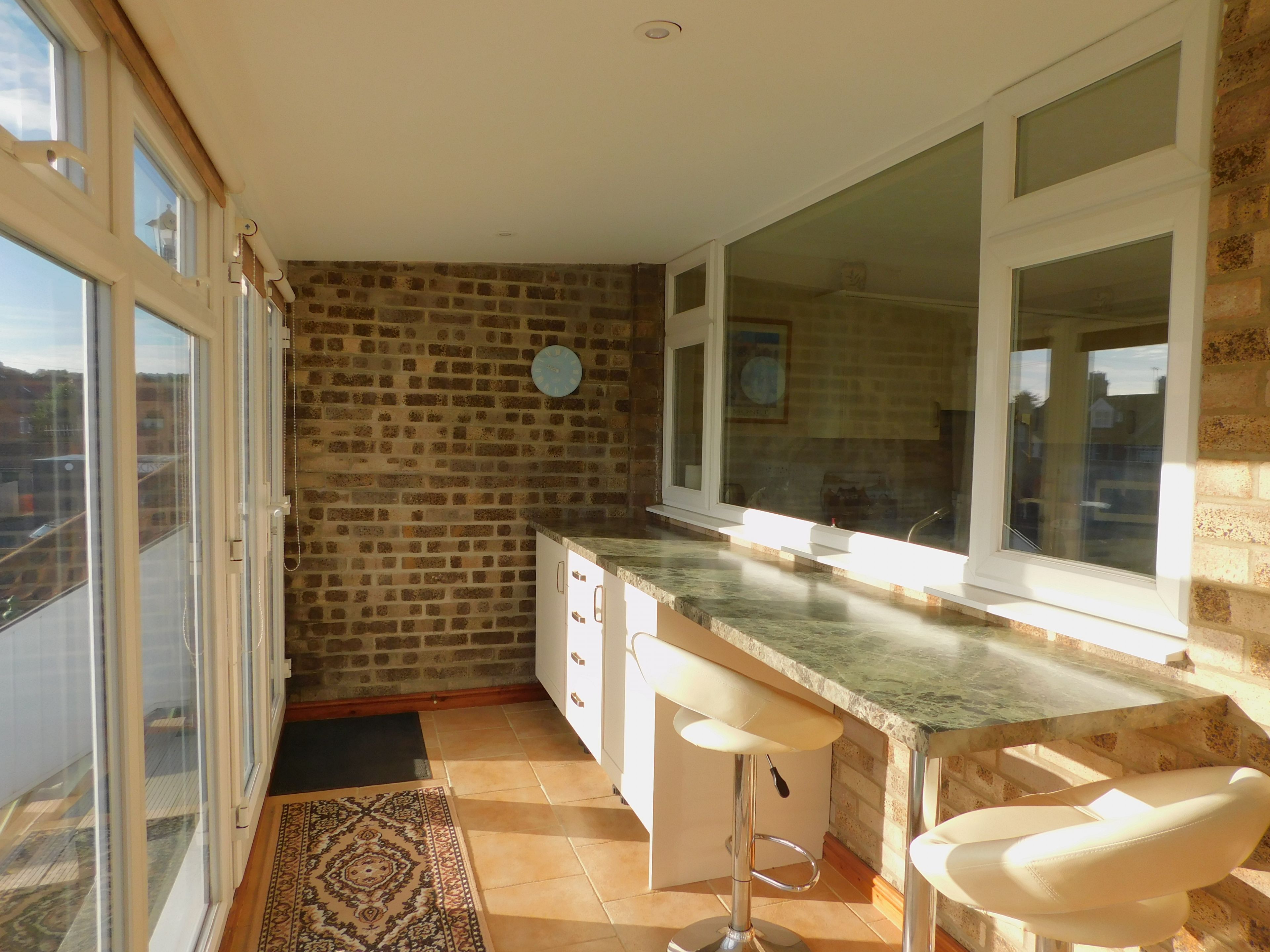 A kitchen with a brick wall, large windows, and a bar stool.