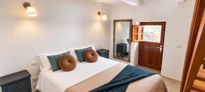 Une chambre à coucher avec un lit, des tables de chevet, un miroir et une porte.