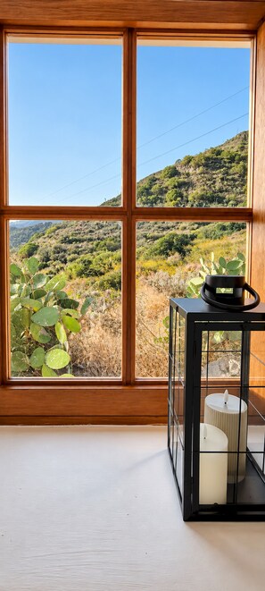 Ein Zimmer mit einem großen Fenster und Blick auf eine hügelige Landschaft.