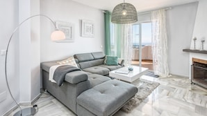 A modern living room with a grey sectional sofa, a coffee table, and a floor lamp. - I02 El Alarife - Apartment with sea views (Sitio de Calahonda)