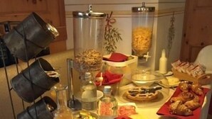 A buffet table with various food items and condiments, including a bottle of juice, a bowl of salad, and a tray of pastries. - Hotel Bes & Spa (Claviere)
