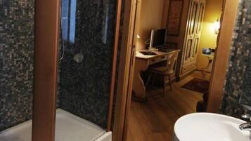 Ein Badezimmer mit Dusche, Waschbecken und einem Schreibtisch.