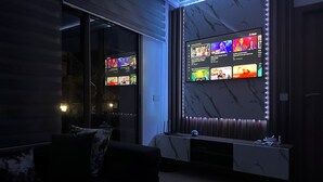 A modern living room with a large wall-mounted TV displaying various content. - High standing apartment PERLA SAIDIA 3min walk from the beach (Saïdia)
