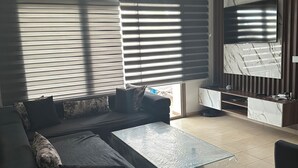 A modern living room with a sectional sofa, a coffee table, and a TV mounted on the wall.