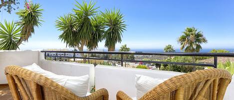 A balcony with wicker furniture and a view of the sea.