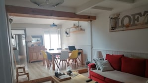 Ein Wohnzimmer mit einem roten Sofa, einem Holztisch und einem Essbereich mit Tisch und Stühlen.