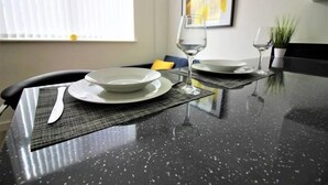 A dining table with a black speckled surface, a white plate, a wine glass, and a placemat. - Overnight Stay Chester With Parking (Chester)