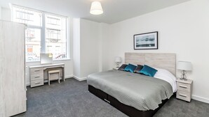 Une chambre moderne avec un lit, des tables de chevet, un bureau et une fenêtre.