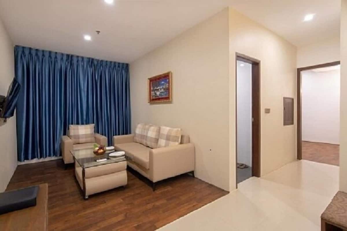 Una sala de estar con un sofá, una mesa de centro y un televisor. Hay una puerta que da a otra habitación.