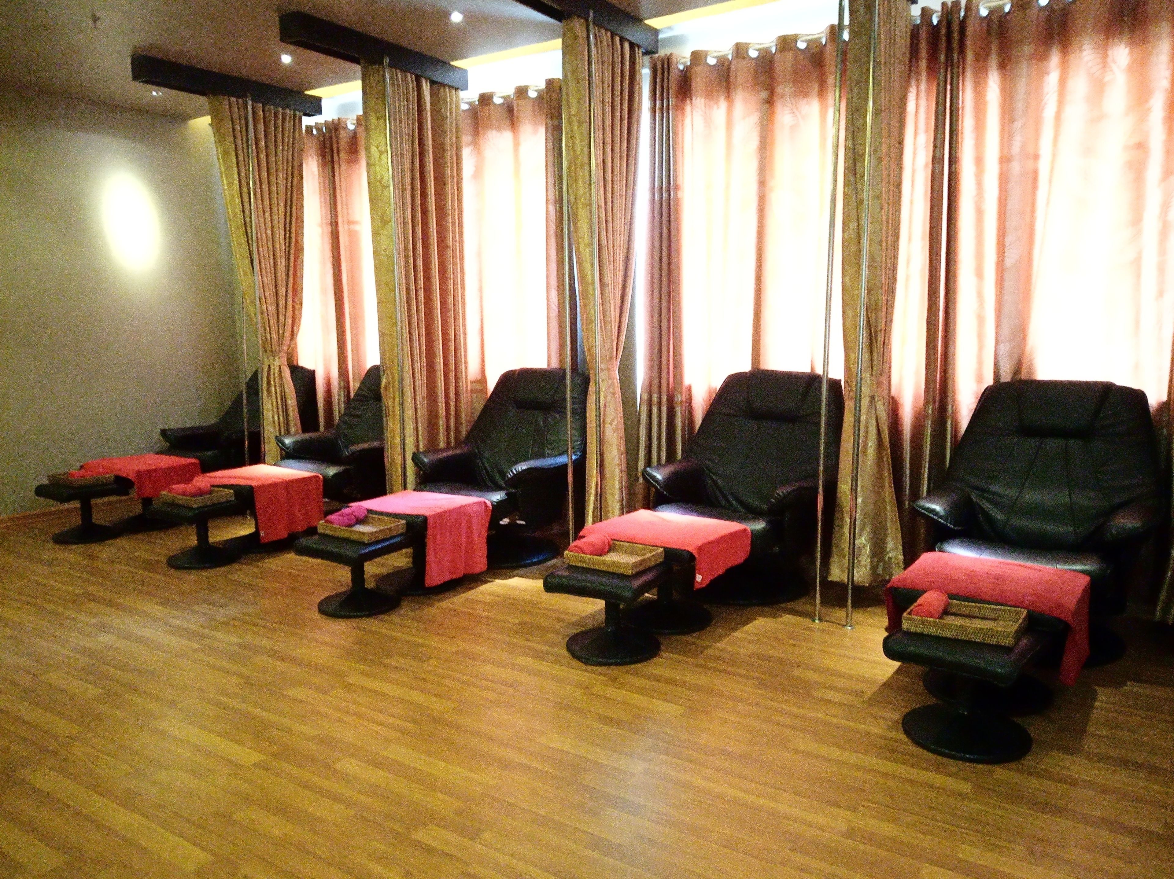 A room with multiple massage chairs, each with a small table and a red cloth.