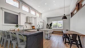 A modern kitchen with a central island, bar stools, and a dining table with chairs. - LaFave-Luxury Home at Zion: West Temple (Springdale)