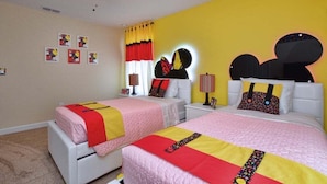 Ein Schlafzimmer mit zwei Betten, einem Deckenventilator und einer gelben Wand.